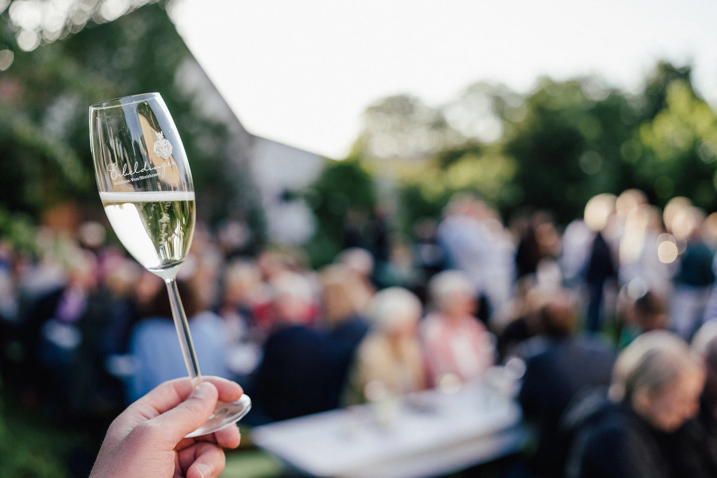 Sektglas mit Gästen beim Erbeldinger Event im Garten