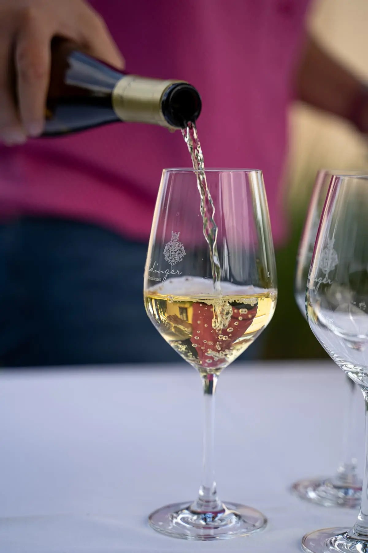 Weinglas wird mit Erbeldinger Weißwein aufgefüllt